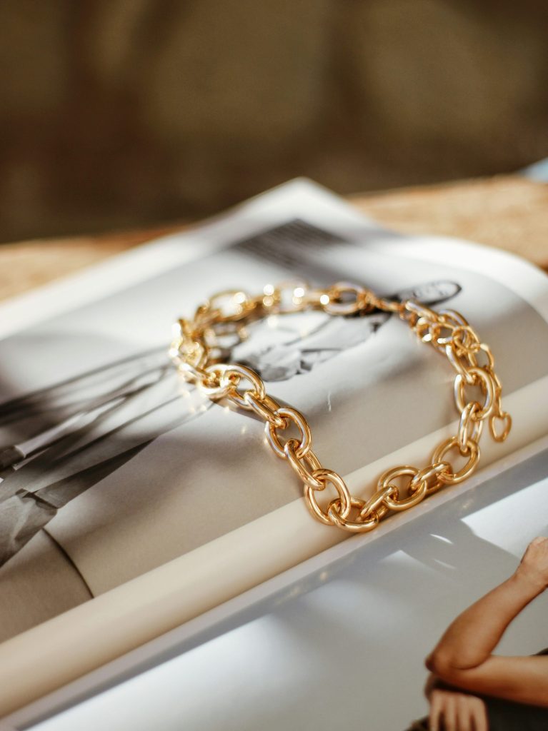 Una pulsera de cadena de oro encima de una revista.