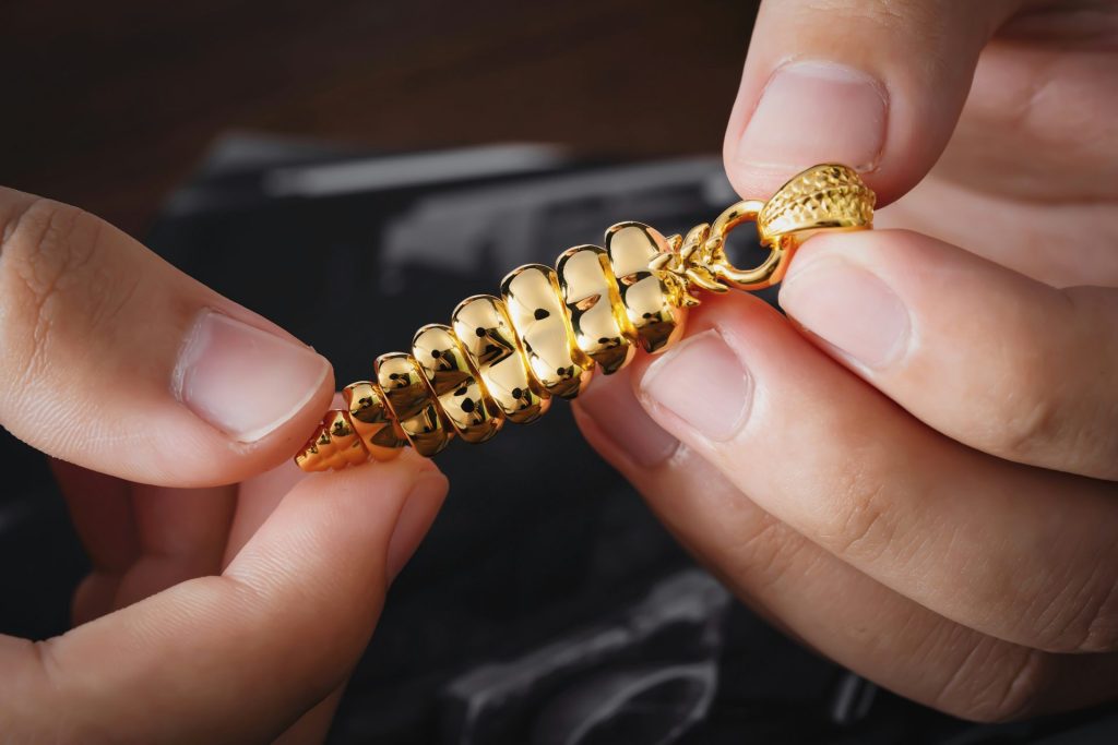 Una persona sostiene una cadena de oro con un broche.